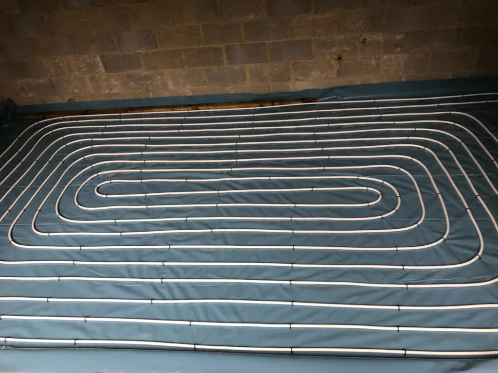Underfloor heating pipe loops on grooved floor panels