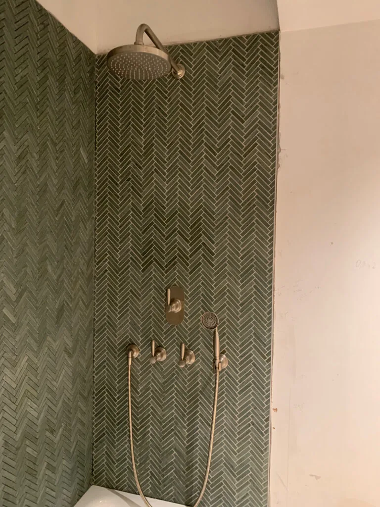 Shower fittings against green wall tiles