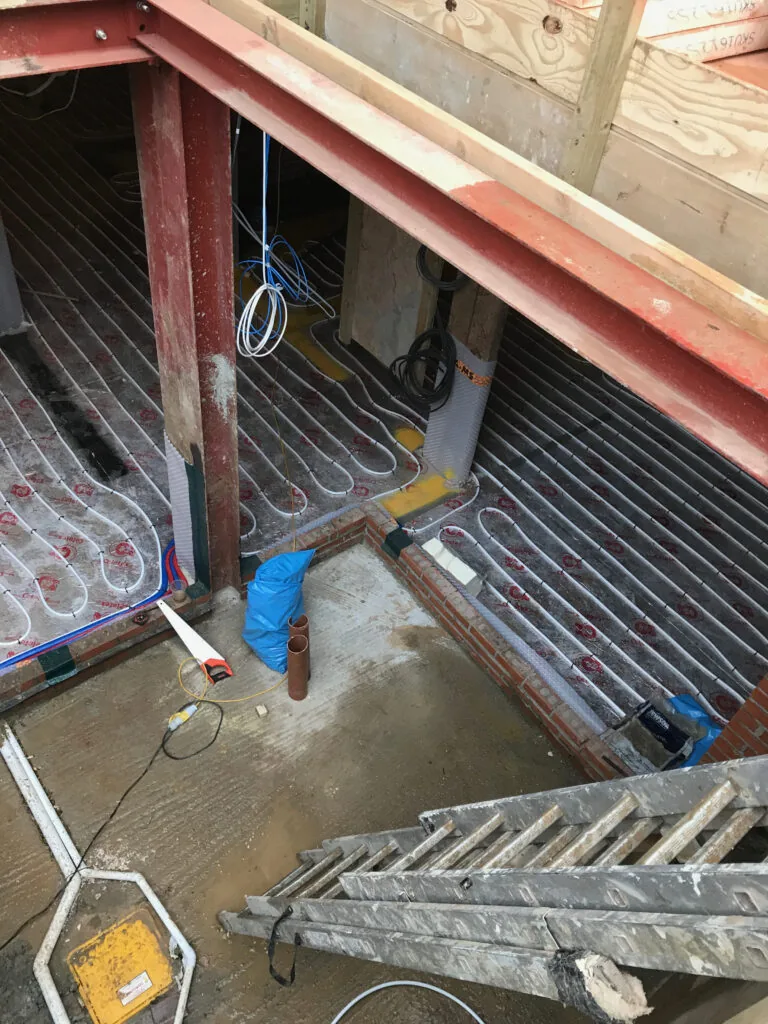 Underfloor heating pipe loops below a steel beam