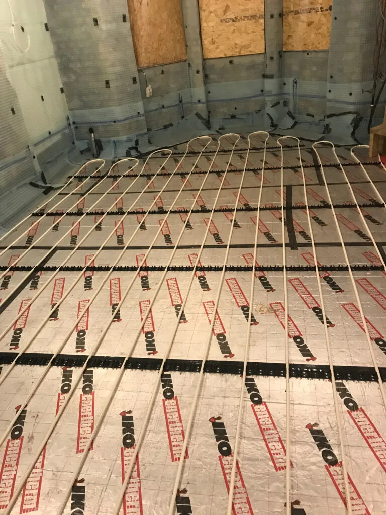 Heating pipe loops laid across a room before floor finishing