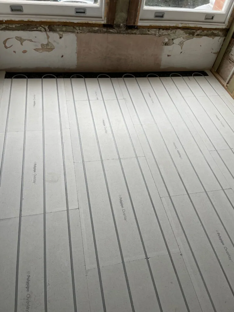 Heating pipes in floor panels before the floor covering