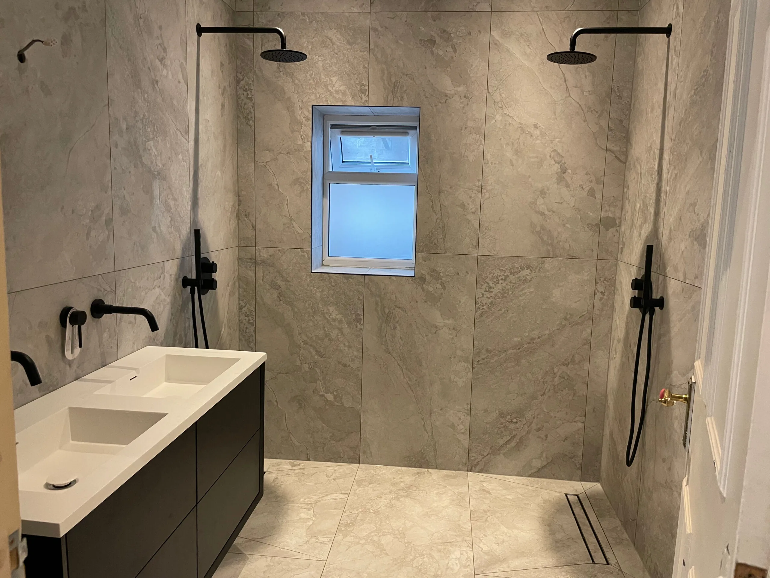 Bathroom vanity and tiled shower area with overhead shower fittings