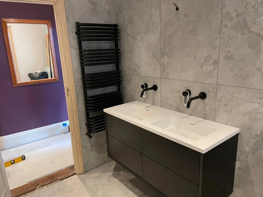 Wall-mounted double-basin vanity with black taps and towel radiator