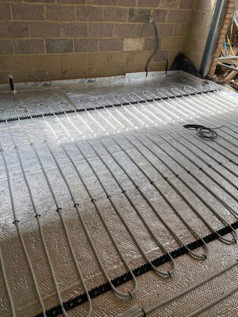 Underfloor heating pipes clipped over foil-faced insulation