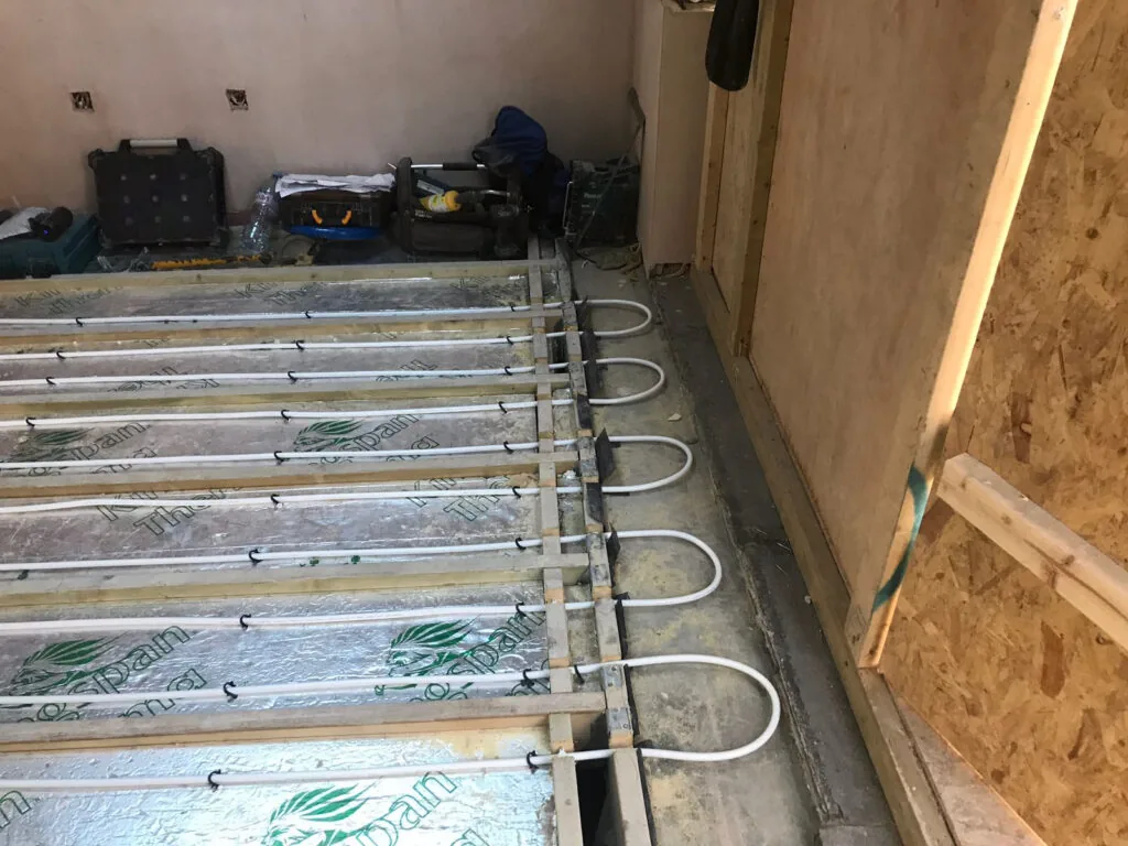 Underfloor heating pipes and metal heat-spreader plates