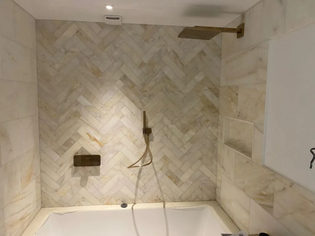 Bath, shower fitting and recessed shelf in a tiled bathroom